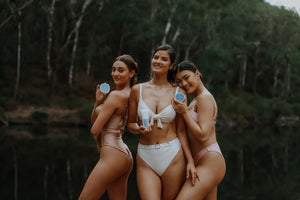 three models standing in their swimwear holding wild fusion skincare cleansers