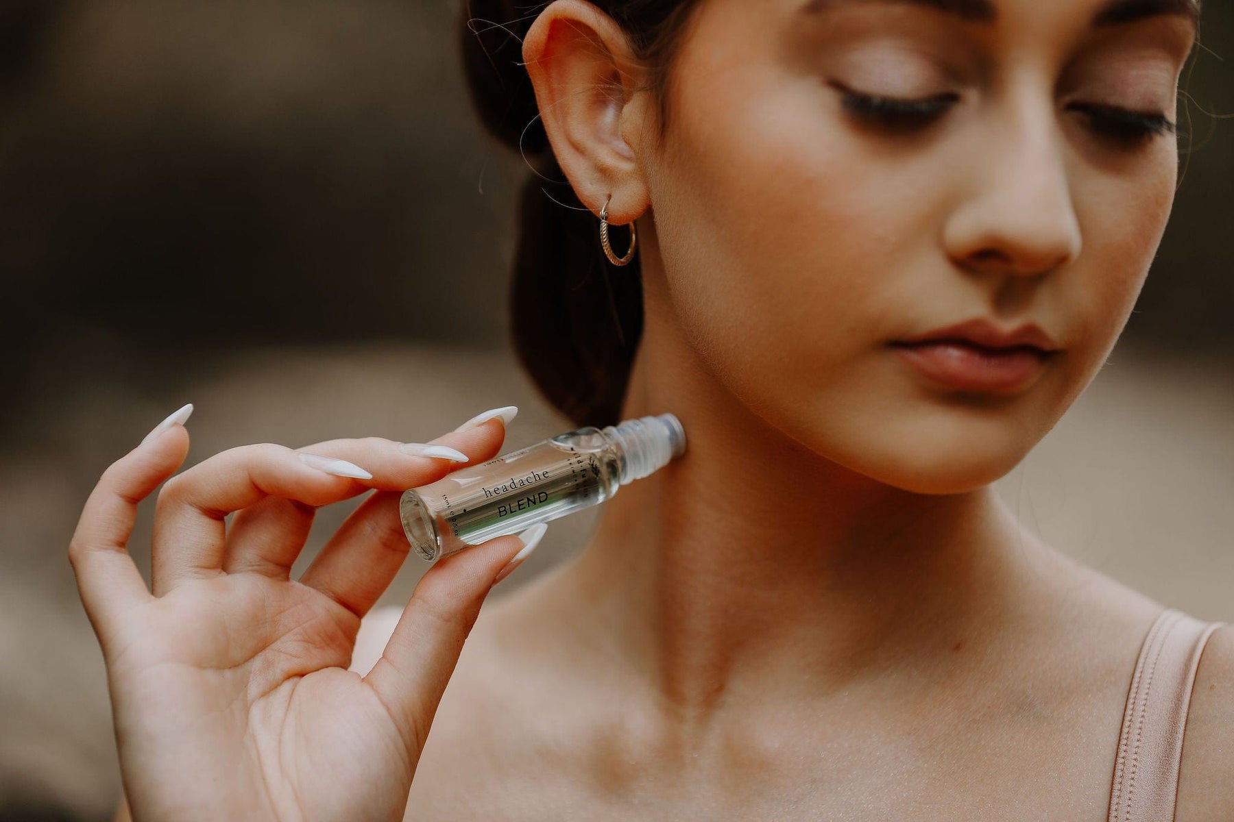 model with closed eyes applying wild fusion skincare temple roller headache blend to her neck