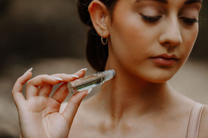 model with closed eyes applying wild fusion skincare temple roller headache blend to her neck